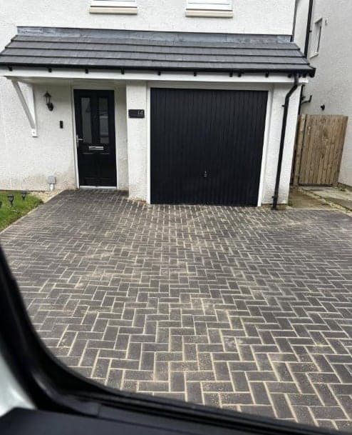 Block paving to a black garage, cleaned by Steam King